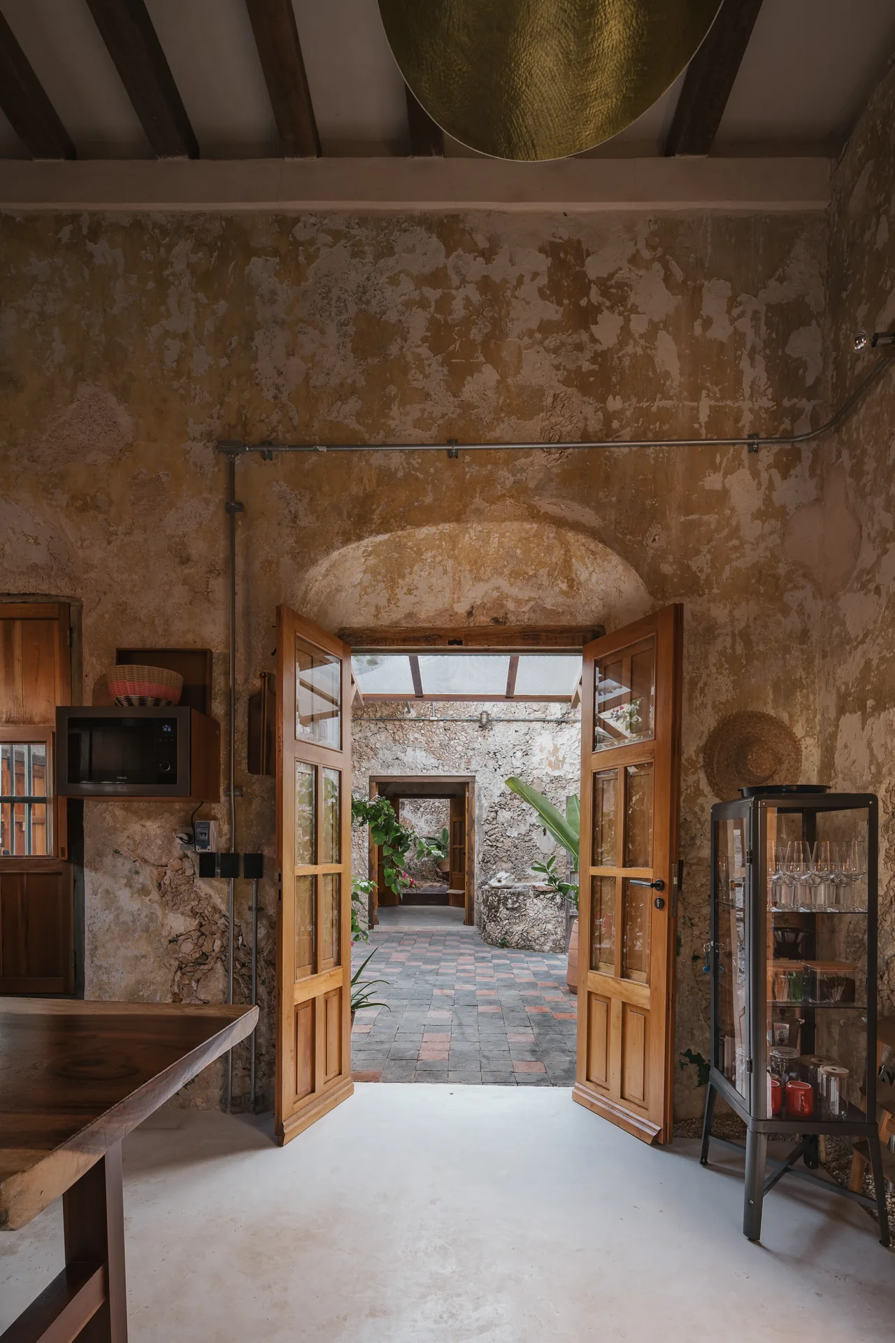 Interior con arco colonial de piedra y muros restaurados en una casa histórica de Campeche — Casa Zotz by Casonas MX